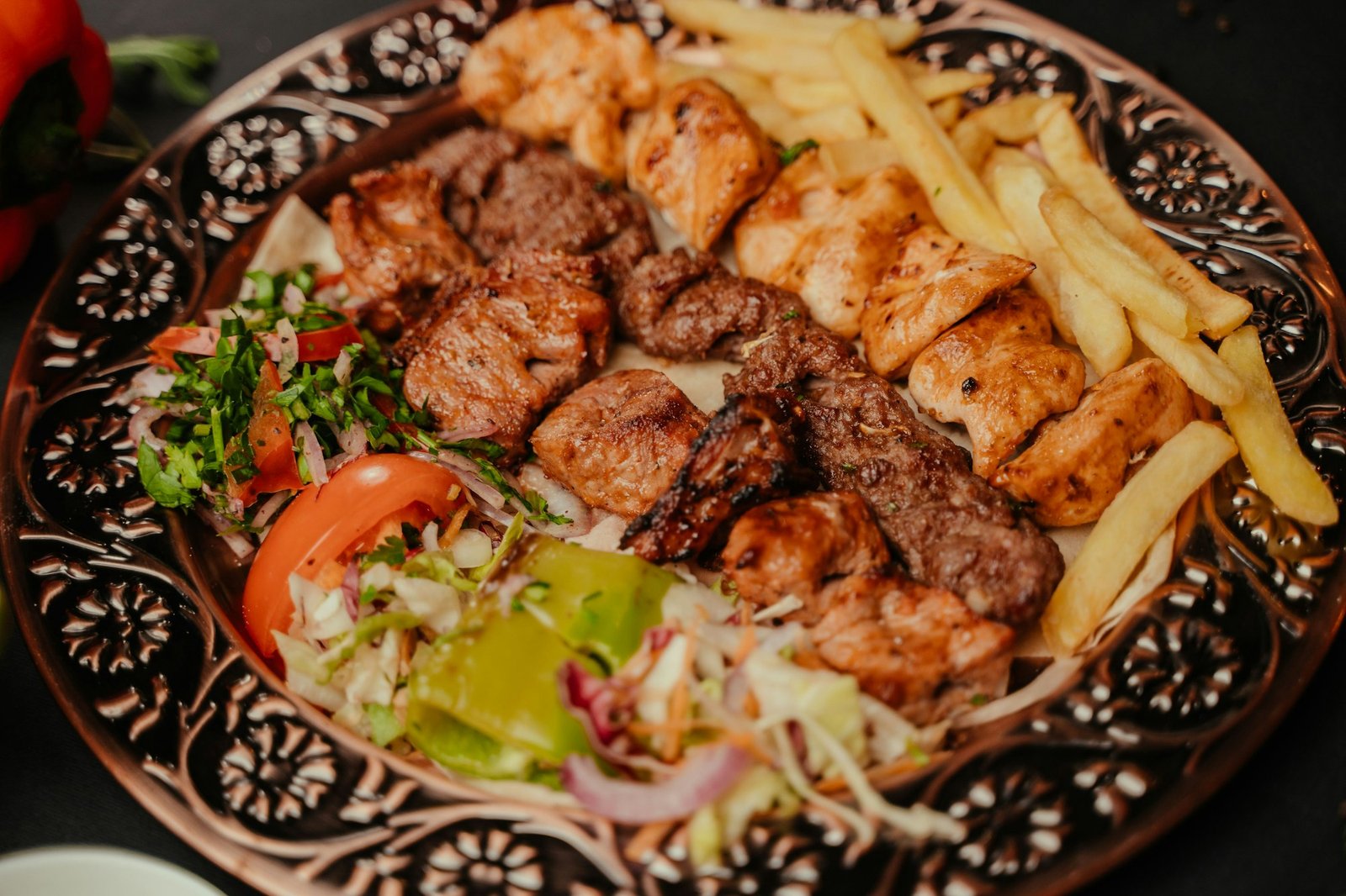 Plate filled with a variety of culinary delights, including fries and freshly made kebab